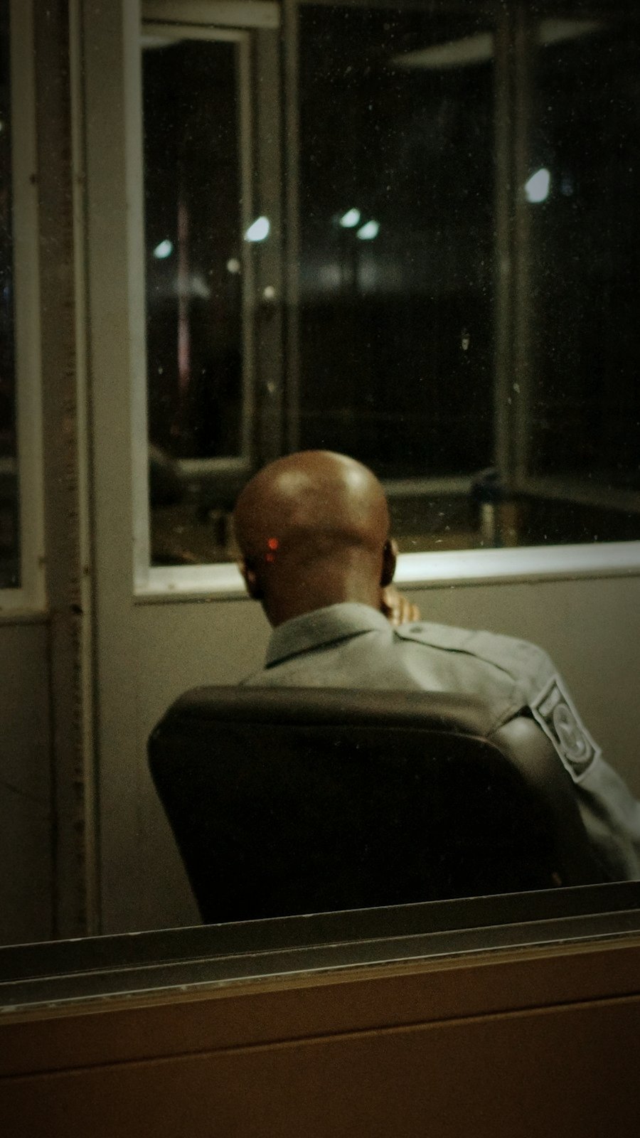 Tactical officer seen from behind with POLICE on the vest, emergency lights in the background