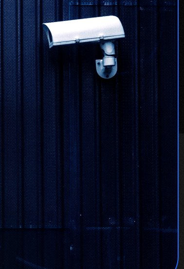 White security camera mounted on a dark corrugated wall